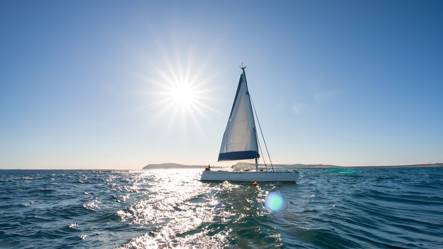 A-Contessa-32-sailboat-sailing-in-the-ocean-with-waves-and-sun-rays-in-the-background-1