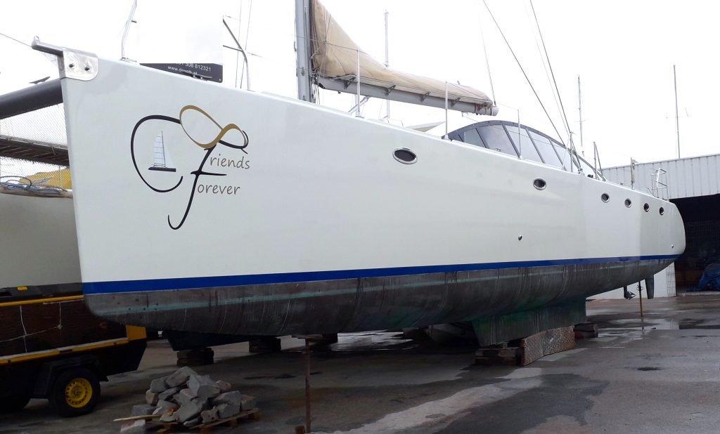 A white twin-hulled cruising catamaran named Friends Forever lying afloat, showing her wide bridgedeck, raised coachroof windows and single mast