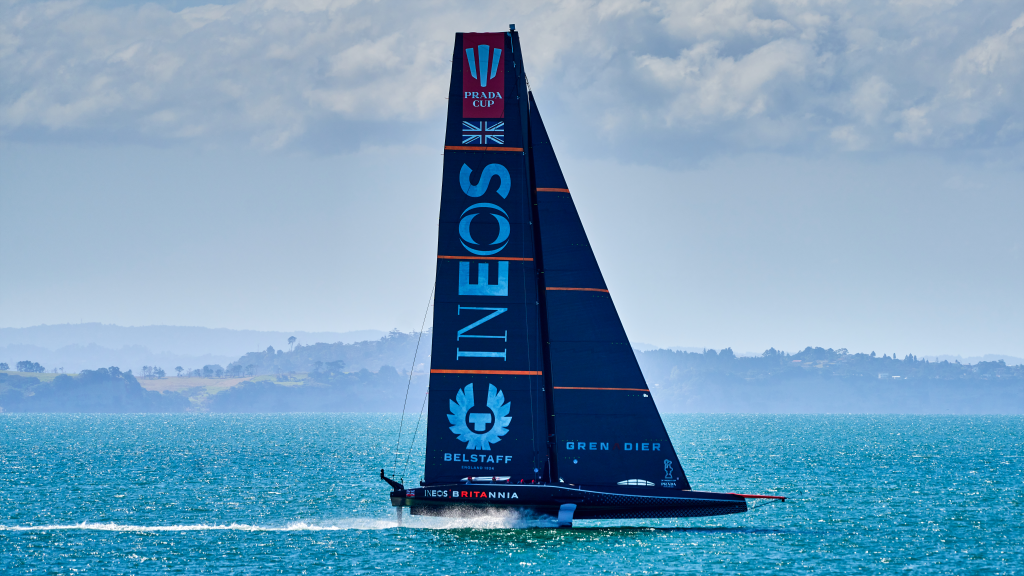 INEOS TEAM UK's AC75 Britannia lifted clear of the water on its hydrofoils, hull flying with spray off the leeward foil arm