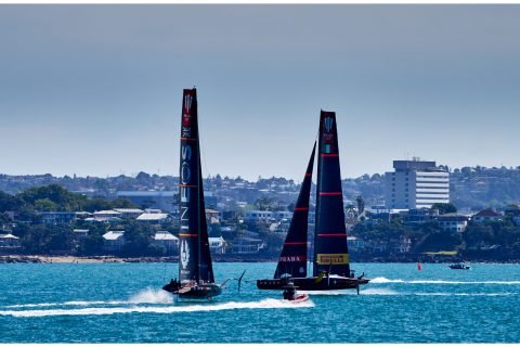 Two AC75 foiling monohulls, Luna Rossa Prada Pirelli and INEOS TEAM UK, sailing towards each other as they enter the pre-start box on flat water