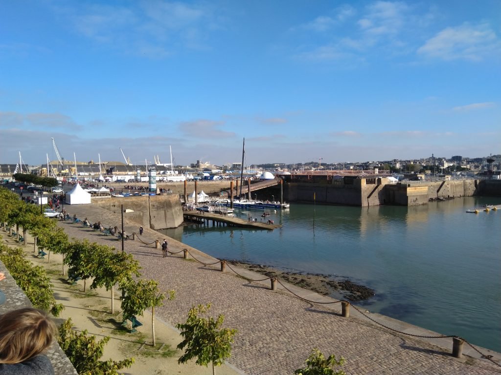 The Ultim trimaran Maxi Banque Populaire IX tied up at Saint-Malo, its long white floats and wingmast towering over the dock