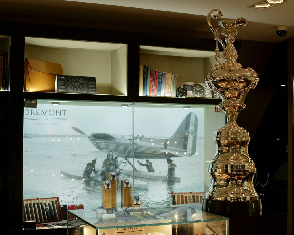 The silver America's Cup trophy, a tall ornate ewer on a wooden plinth, displayed behind glass