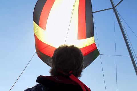 US Yachts US 22 sailboat Vesper with crew member flying the spinnaker